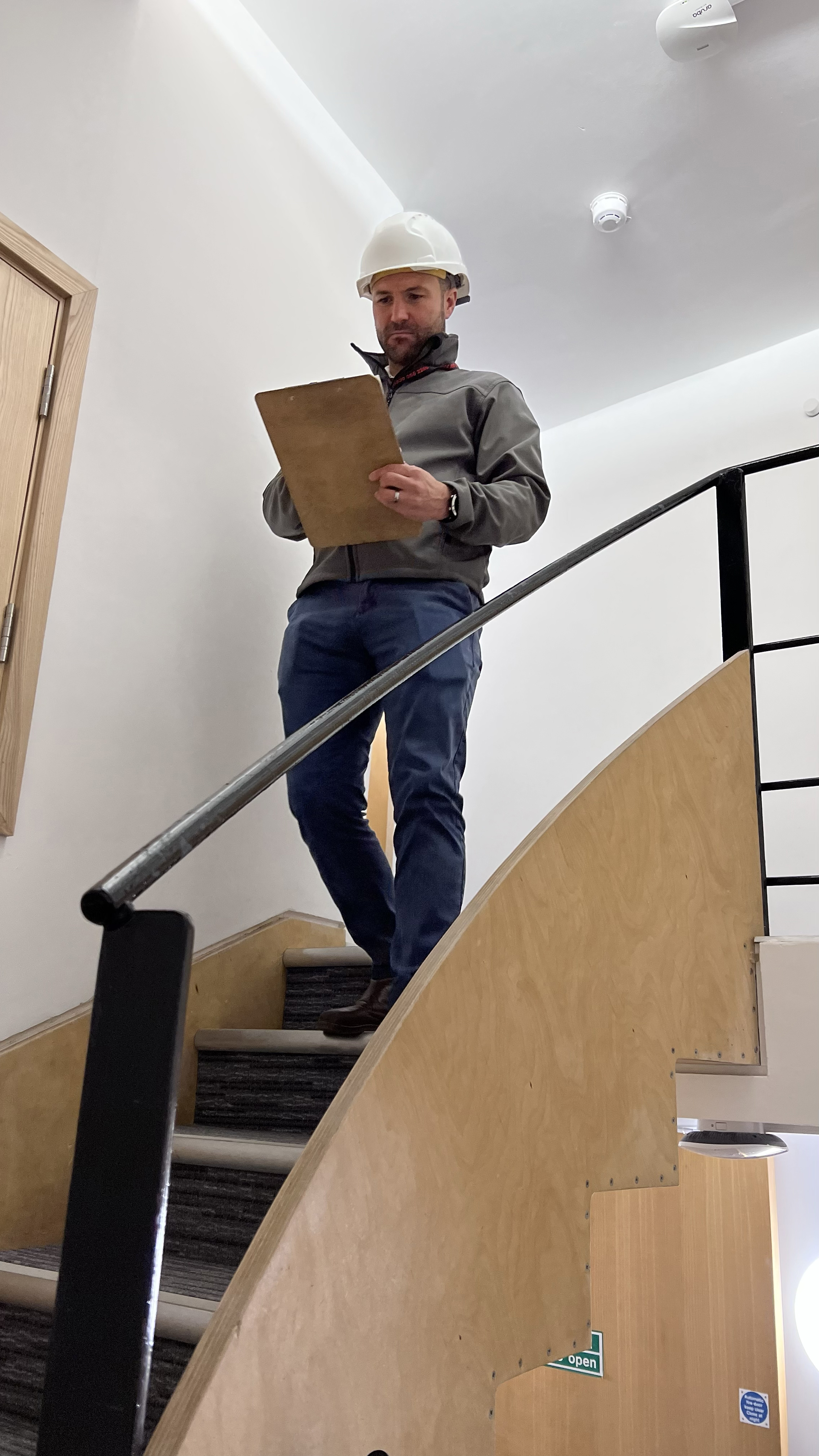 Man in hardhat on Stairs with Clipboard - Fire Prevention
